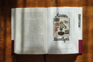 Ein Foto des aufgeschlagenen Buchs. Links der Text, auf der rechten Seite eine Zeichnung und die Schrift Museum Haus Cajeth