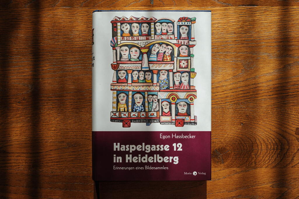 Buchcover. Malerei, viele Halbportraits schauen aus Fenstern. Schrift: Egon Hassbecker, Haspelgasse 12 in Heidelberg, Erinnerungen eines Bildersammlers.